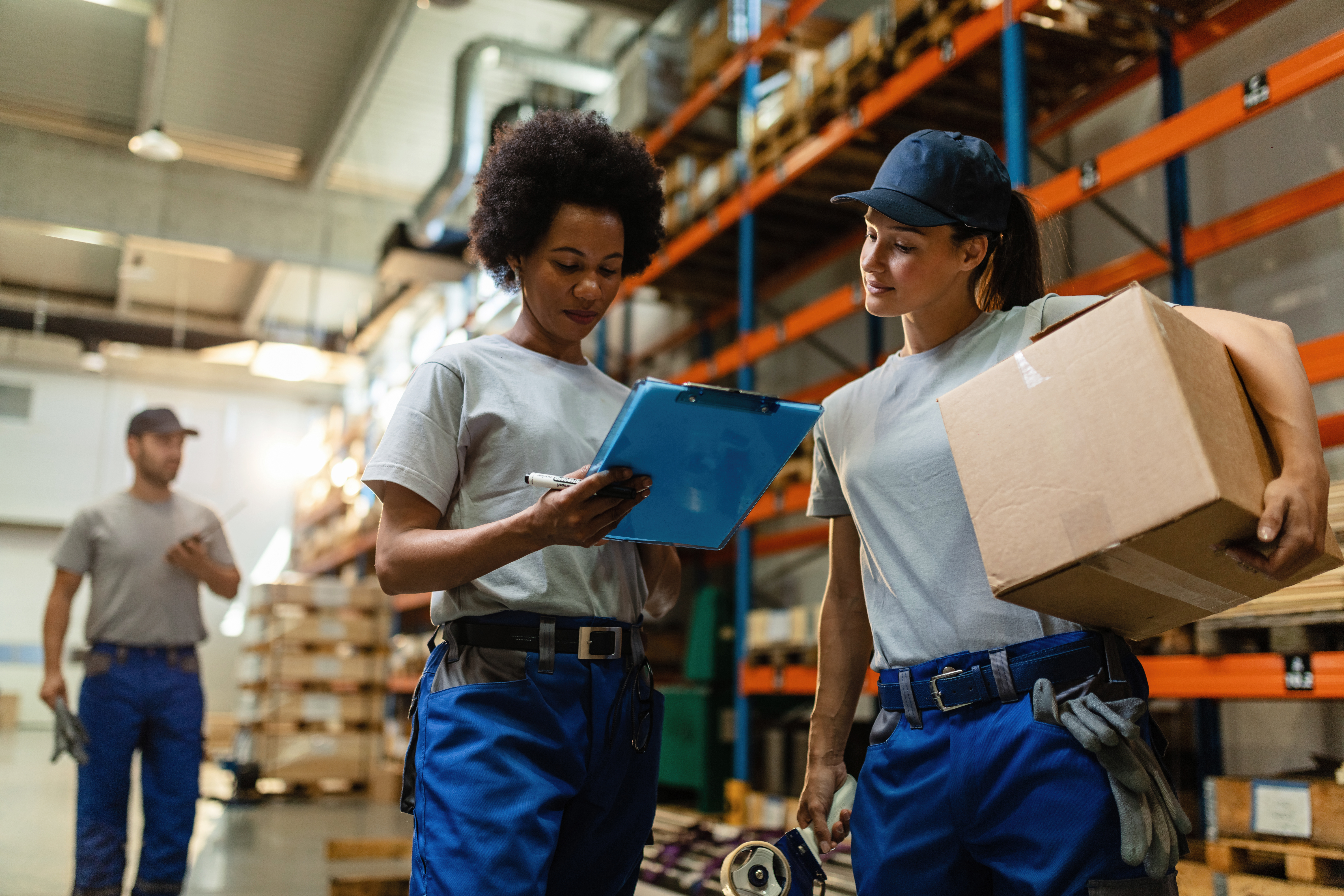 low-angle-view-two-female-workers-reading-delivery-schedule-list-while-working-distribution-warehouse