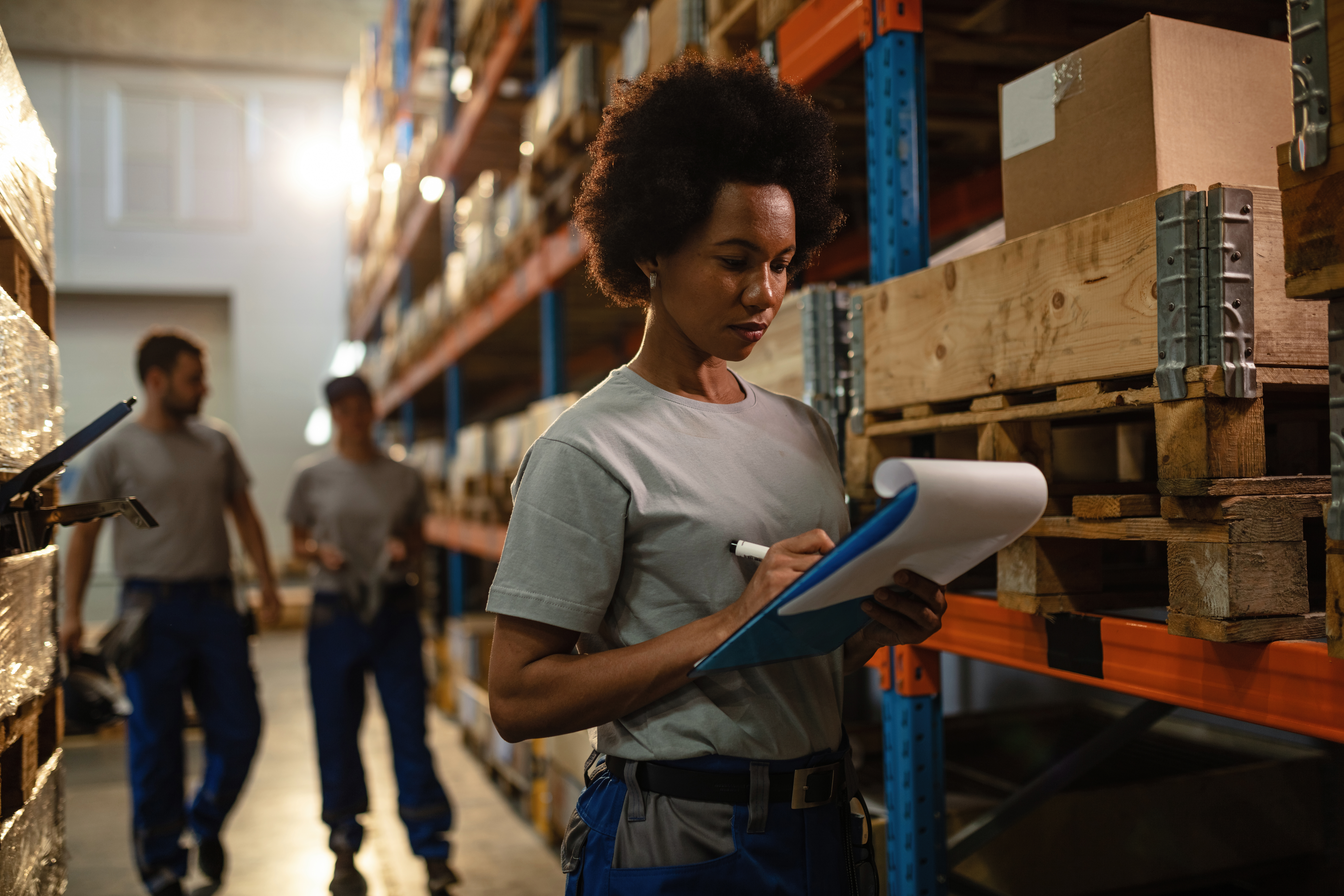 african-american-worker-taking-notes-while-making-shipment-schedule-warehouse.