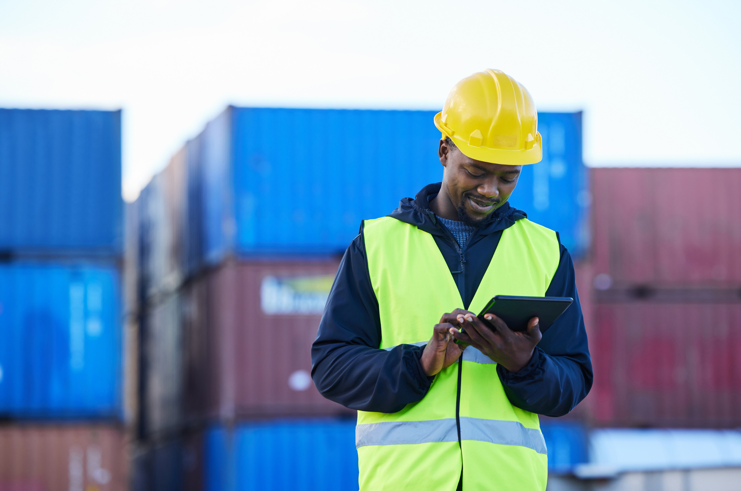 Logistics worker using a tablet to manage freight shipments with a freight management system.